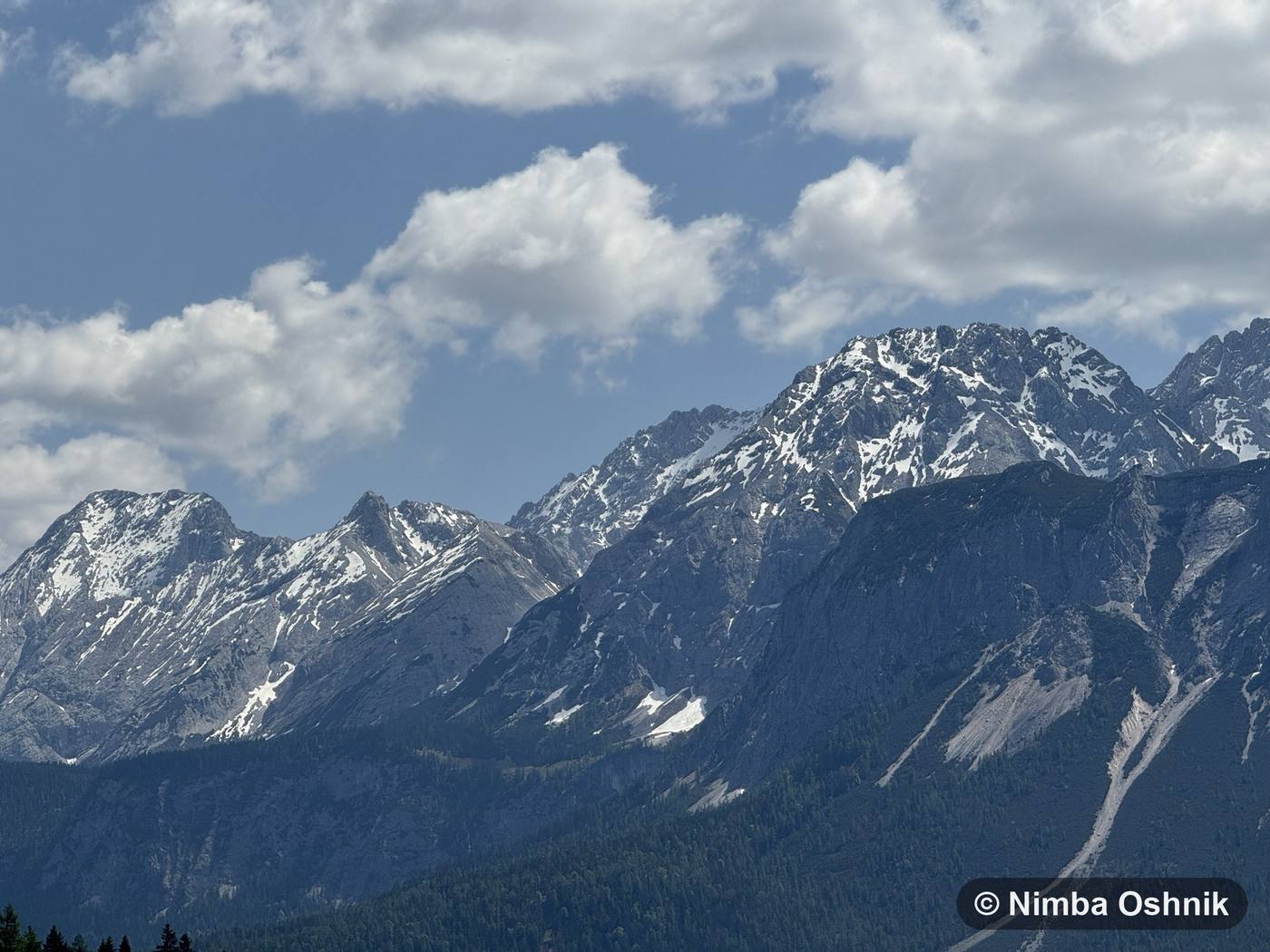 Jagged snow-covered range under a bright sky with scattered clouds