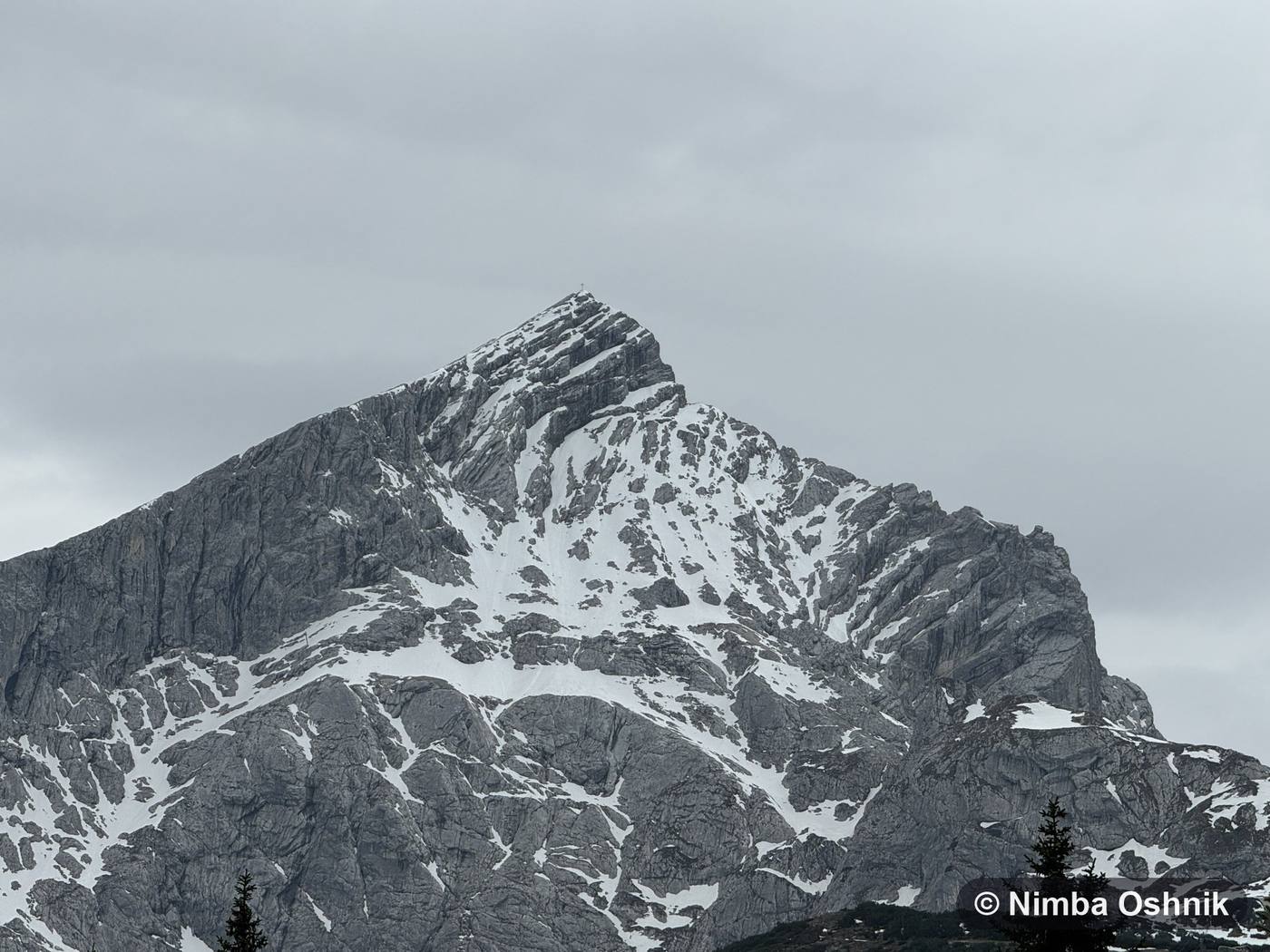 Snow-streaked rocky summit under an overcast sky