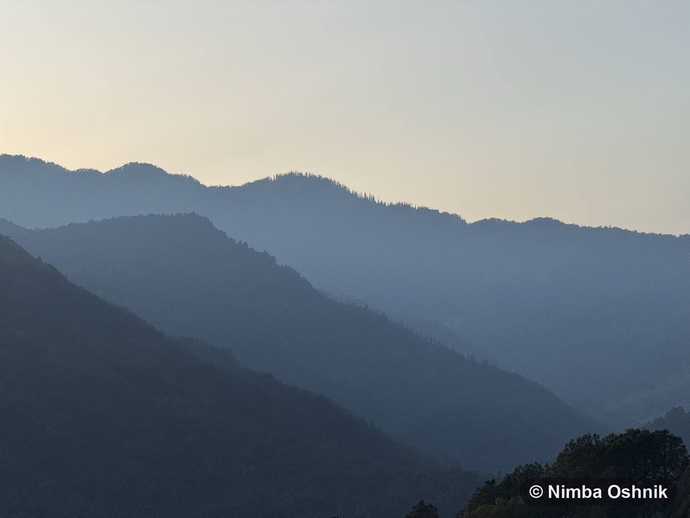 Layered mountain ridgelines fading into evening haze